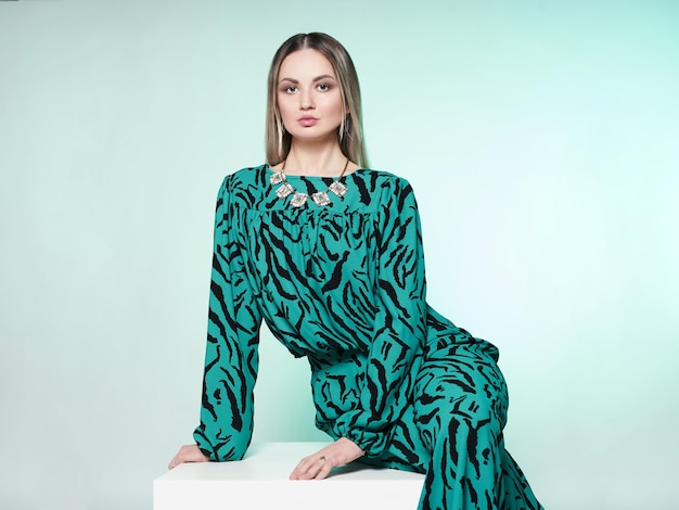 High fashion photo of a beautiful elegant young woman in a beautiful green suit