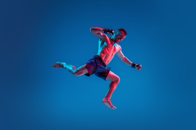 High flight MMA Professional fighter punching or boxing isolated on blue studio background