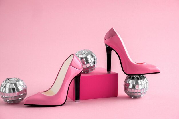 High heel shoes with disco balls on pink background