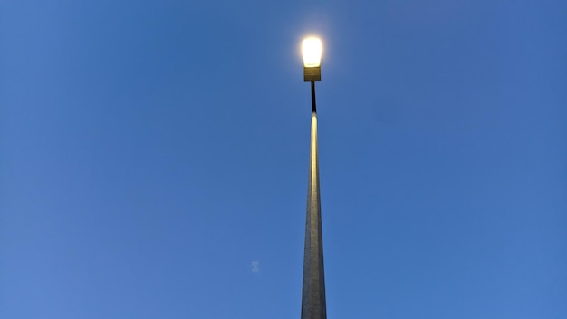 High lamppost in the evening against the blue sky photo from bottom to top