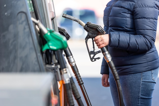 High prices of petrol and diesel fuel ath the petrol station young woman refueling the car economic