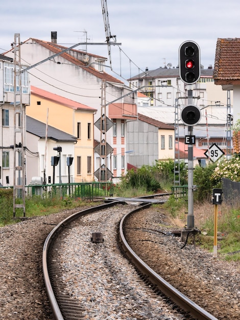 High railway signal for the E1 entrance to the Monforte de Lemos station indicating a stop Red next to its associated beacon and several speed limit signs