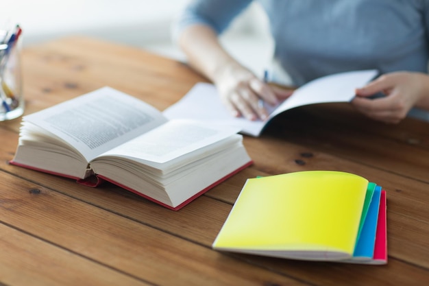 high school, education, people and learning concept - close up of young student or woman with book and notebooks at home