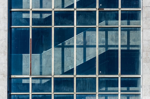 High-tech office building with transparent walls reflecting a bright blue sky with clouds. Modern architecture. Abstract glass background