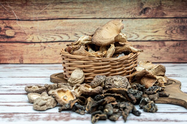 High view of dried pine shiitake and oyster mushrooms in a wicker basket on a rustic wooden table