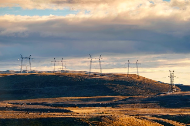 High voltage electric pole on mountain hill among remote wilderness in the sunset at Iceland