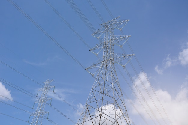 High voltage electric power lines on pylons in blue sky