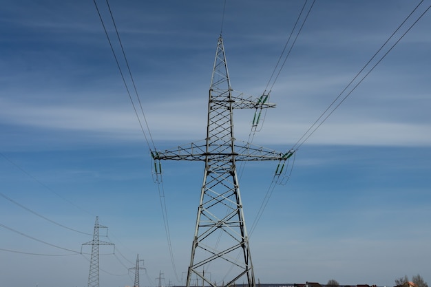 High voltage lines and power pylons on a sunny day with cirrus clouds in the blue sky. Copy space