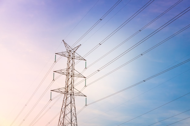 High voltage post tower with blue sky before sunset background.