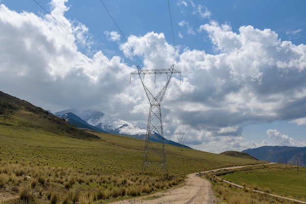 High voltage power pylon in the mountains at sunset Cloudy sky Mountain background