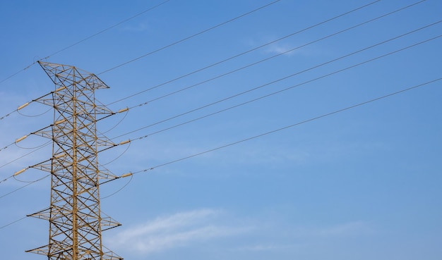 High voltage power transmission tower under the sunny blue sky with copy space