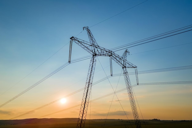 High voltage towers with electric power lines at sunset