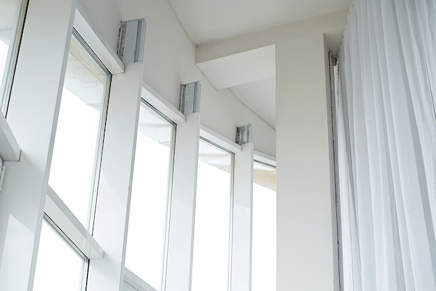 High white plastic panoramic windows and white curtains in a bright apartment