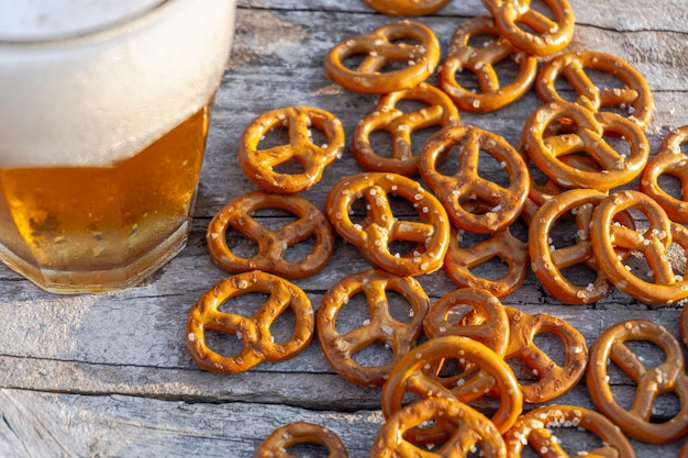 Highangle of salted pretzels and a cup of beer on a wooden surface