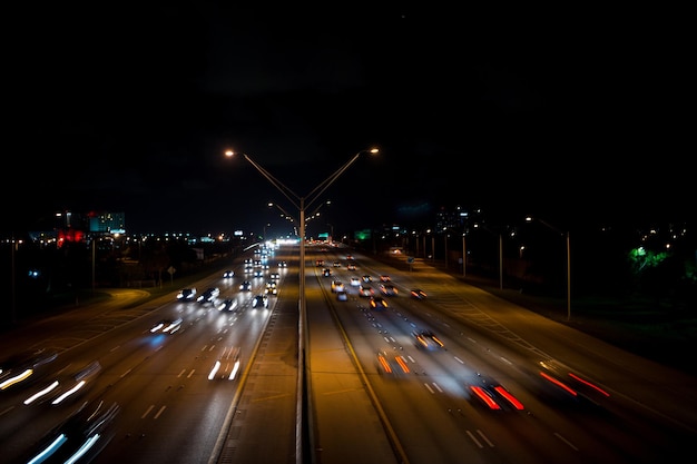 Highway road with car trails at night on dark sky background. Traffic, speed, motion concept. Transport, transportation, travel, trip