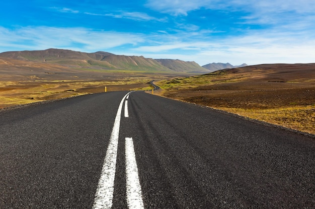 Highway through gravel lava field landscape under a blue summer sky