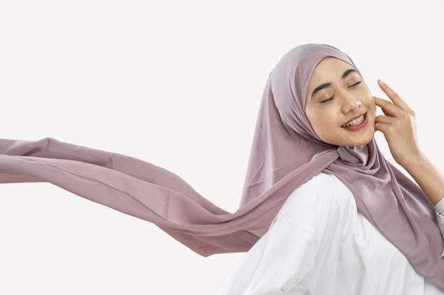 Hijab girl enjoying wearing a purple veil waving in the wind with a hand gesture on the cheek