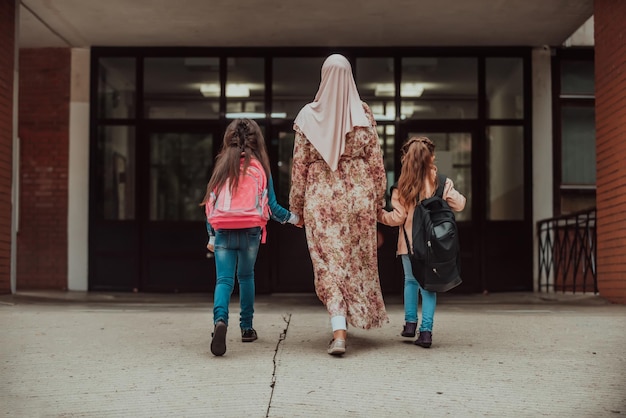 Hijab Muslim mother walking her kids to school Selective focus High quality photo