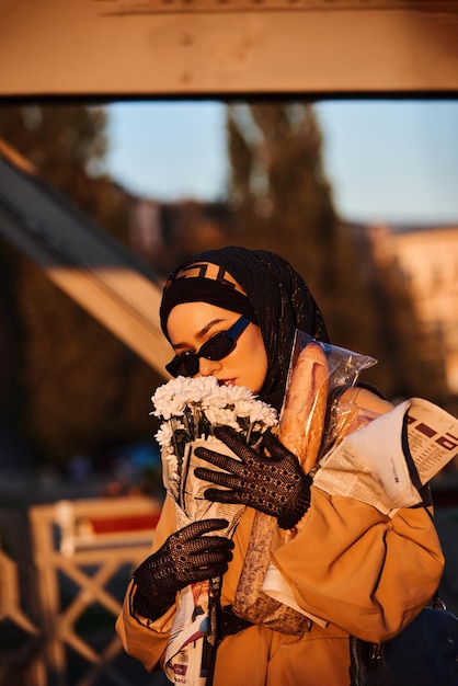 A hijab woman in stylish sunglasses and an elegant french outfit walking through the city at sunset