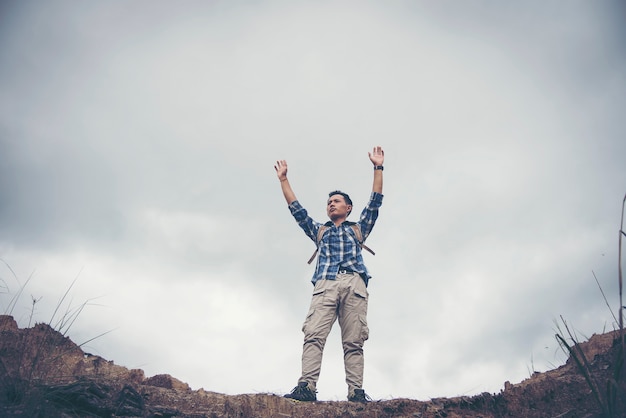 Hiker cheering elated and blissful with arms raised in the sky after hiking.