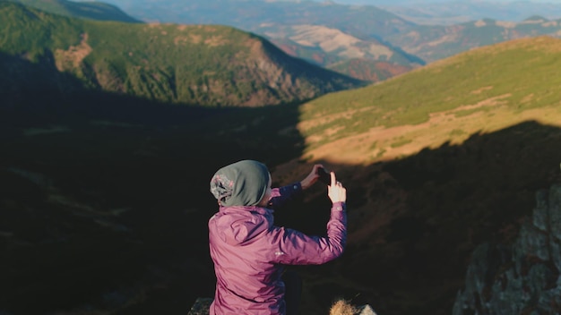 Photo hiker girl making panoramic photo of mountains