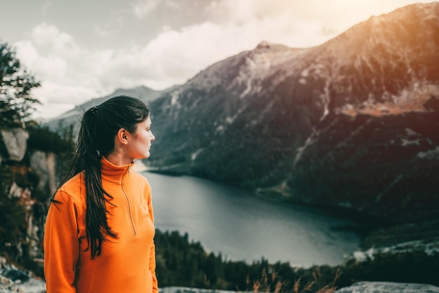 Hiker girl standing at the top Successful woman hiker open arms on a mountain top Girl in a sports outfit in the mountains