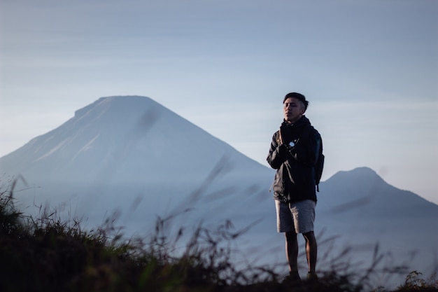 Hiker on the hill with the backpack on his shoulders In the background a beautiful view