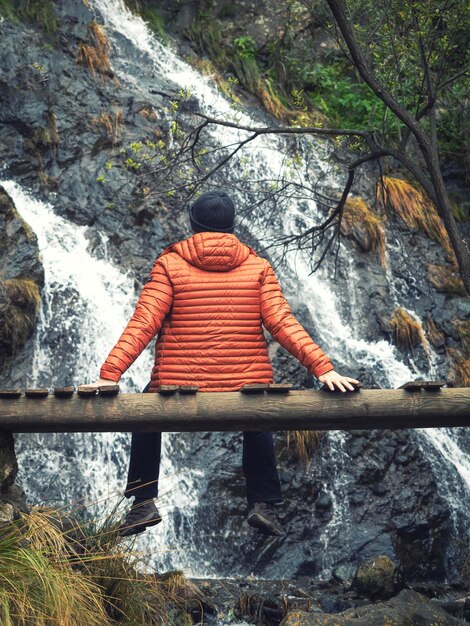 Photo hiker looking at a waterfall sitting on a bridge