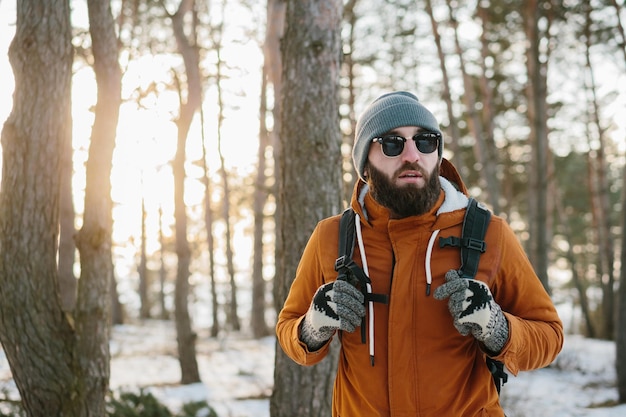 Hiker male walking with backpack in snowy winter forest