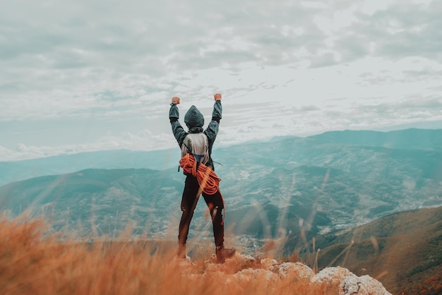 Hiker man celebrates victory on the top mountain