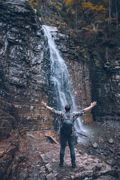 Hiker man looking at autumn waterfall copy space