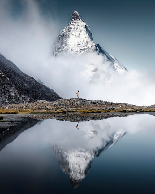 Hiker man walks alone through the incredible Swiss Alps with the Matterhorn in the background betwee