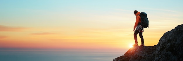 Photo hiker reaching summit at sunrise with stunning ocean view a lone hiker stands on a rocky clif