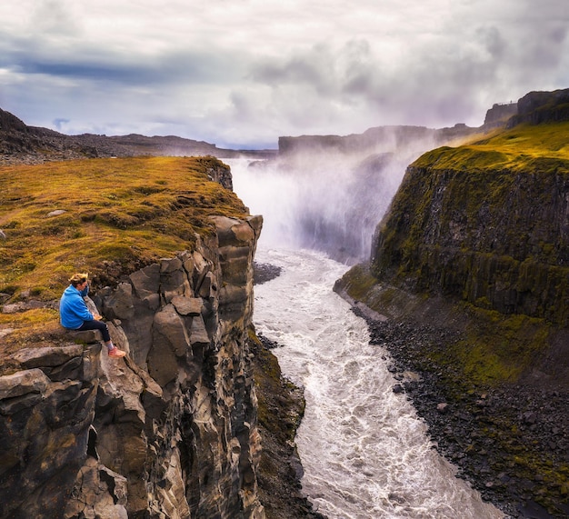 Hiker sitting at the edge of the gullfoss waterfall in iceland