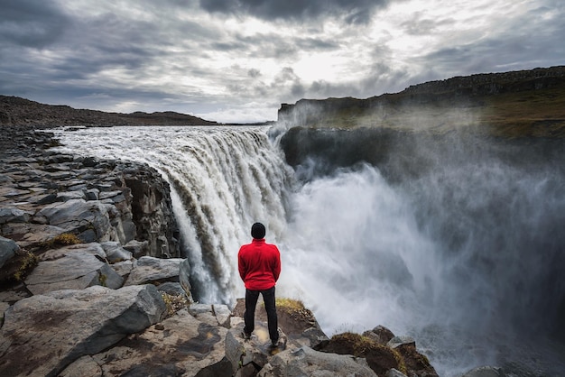 Hiker standing close to the dettifoss waterfall in iceland