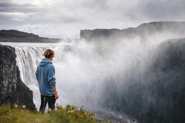 Hiker standing at the edge of the Dettifoss waterfall in Iceland