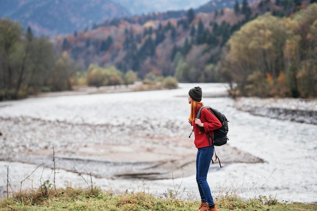 Hiker with a backpack on the banks of the river in the mountains and landscape morning model tourism