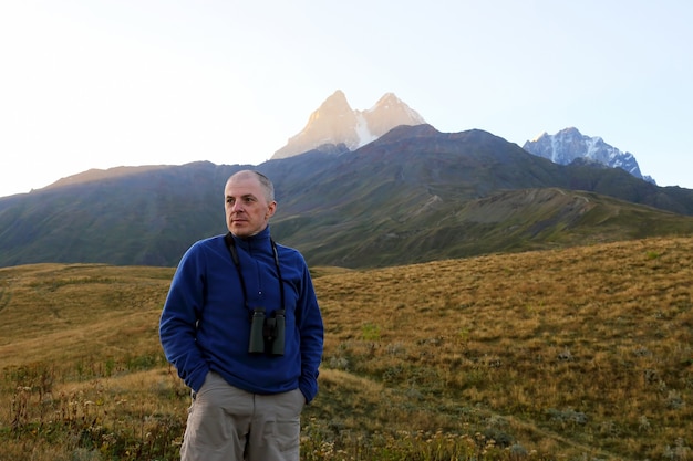 Hiker with binoculars stands on mountains. Svaneti, Georgia