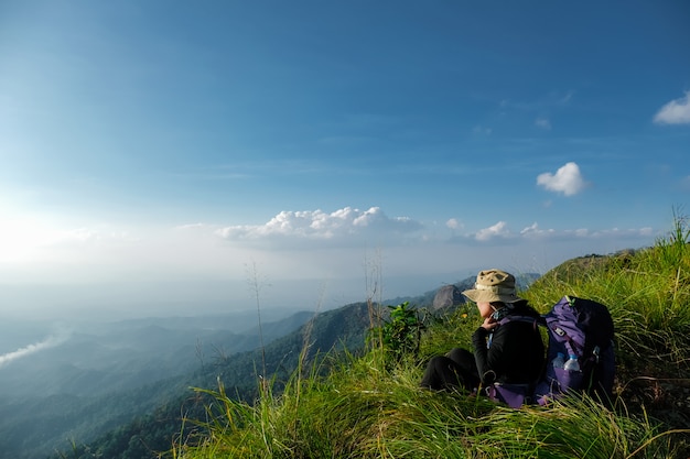 Hiker woman sitting on green grass on the cliff of mountain