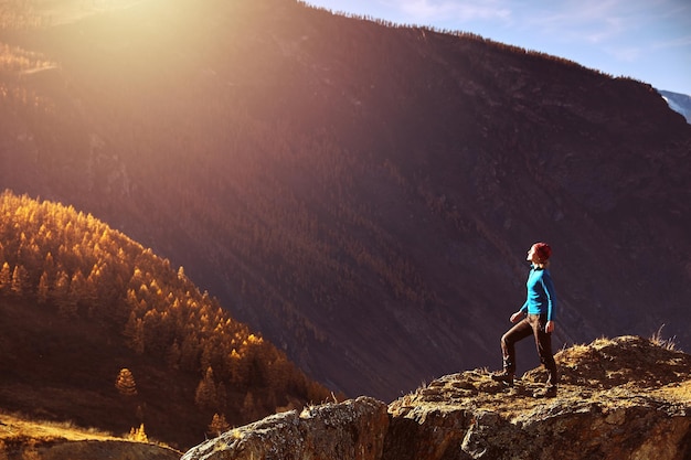 Hiker woman with backpack on rock of a mountain and enjoying sunrise. Travel Lifestyle success concept adventure active vacations outdoor mountaineering sport