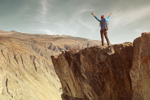 Hiker woman with backpack on rock of a mountain and enjoying sunrise Travel Lifestyle success concept adventure active vacations outdoor mountaineering sport