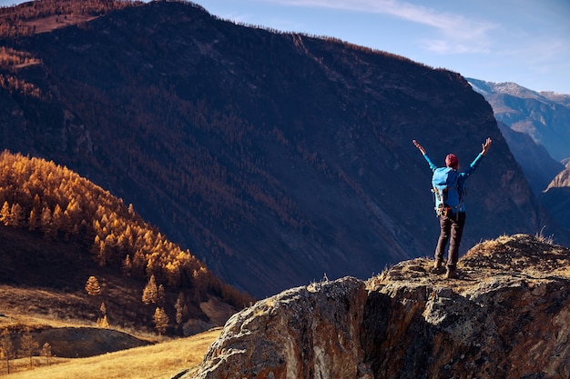 Hiker woman with backpack on rock of a mountain and enjoying sunrise. Travel Lifestyle success concept adventure active vacations outdoor mountaineering sport