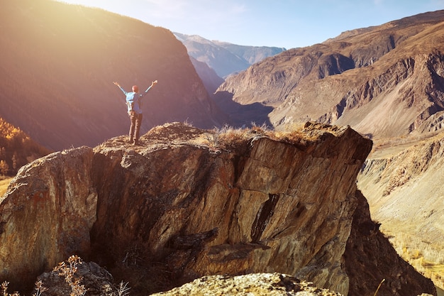 Hiker woman with backpack on rock of a mountain and enjoying sunrise. Travel Lifestyle success concept adventure active vacations outdoor mountaineering sport