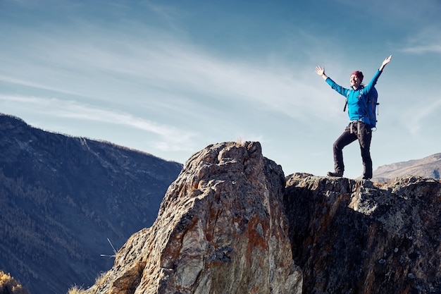 Hiker woman with backpack on rock of a mountain and enjoying sunrise. Travel Lifestyle success concept