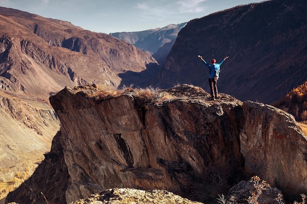 Hiker woman with backpack on rock of a mountain and enjoying sunrise