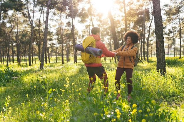 Hikers playing in the forest multiracial couple trekking with backpacks traveling the world