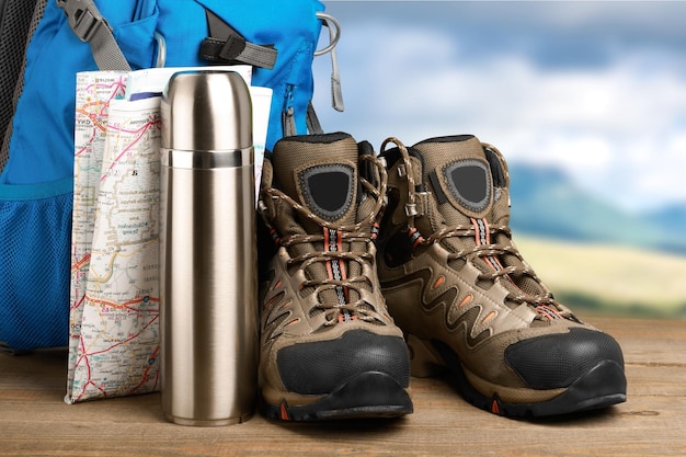 Hiking boots, backpack and map  on background