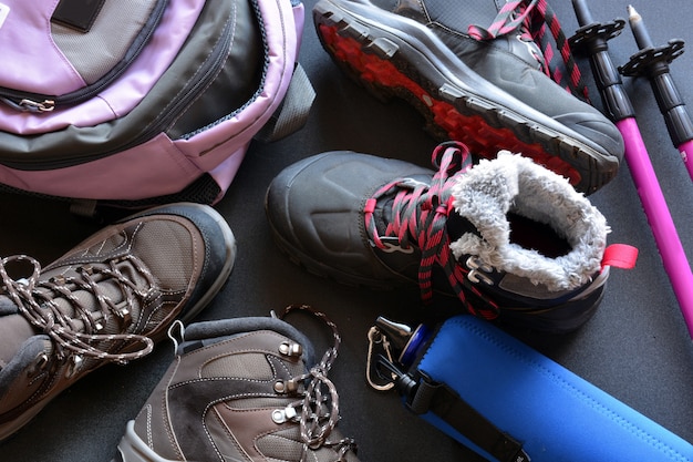 Hiking clothes for women and men, composed of boots, backpack, water bottle and walking sticks