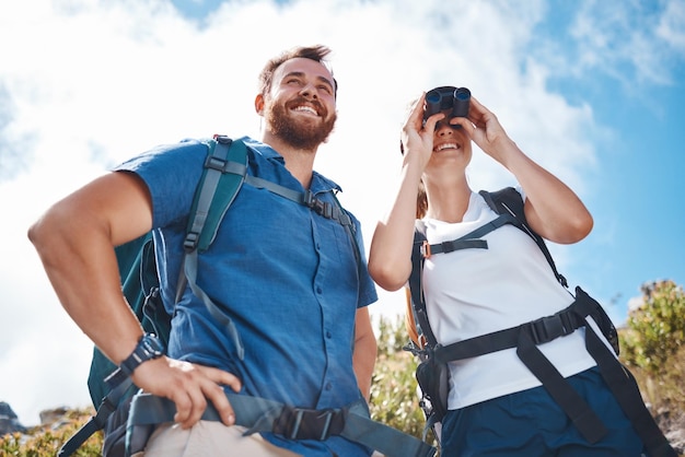 Hiking couple woman using binoculars and adventure happy together with nature sky on travel Smile outdoor man backpack girl happiness and summer trekking holiday on freedom journey in Cape Town