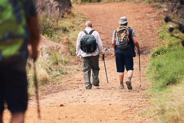 Hiking fitness and friends walking on mountain for adventure freedom and sports in outdoor forest Travel retirement and senior hikers for exercise wellness trekking and cardio workout in nature